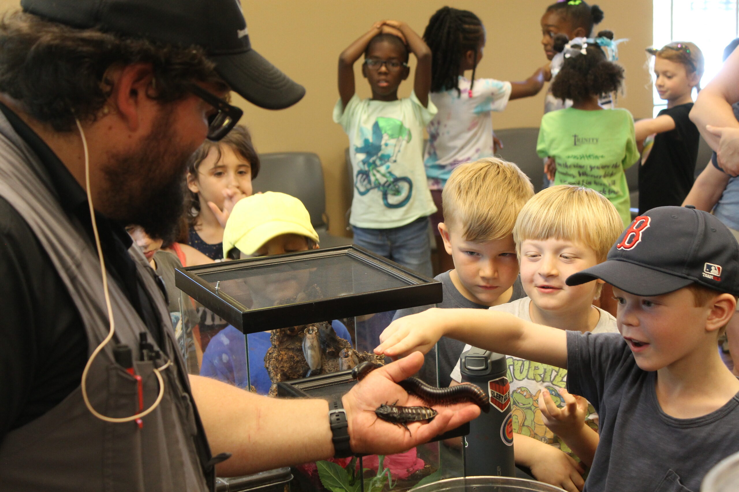 Photo of kids looking at an insect at event.